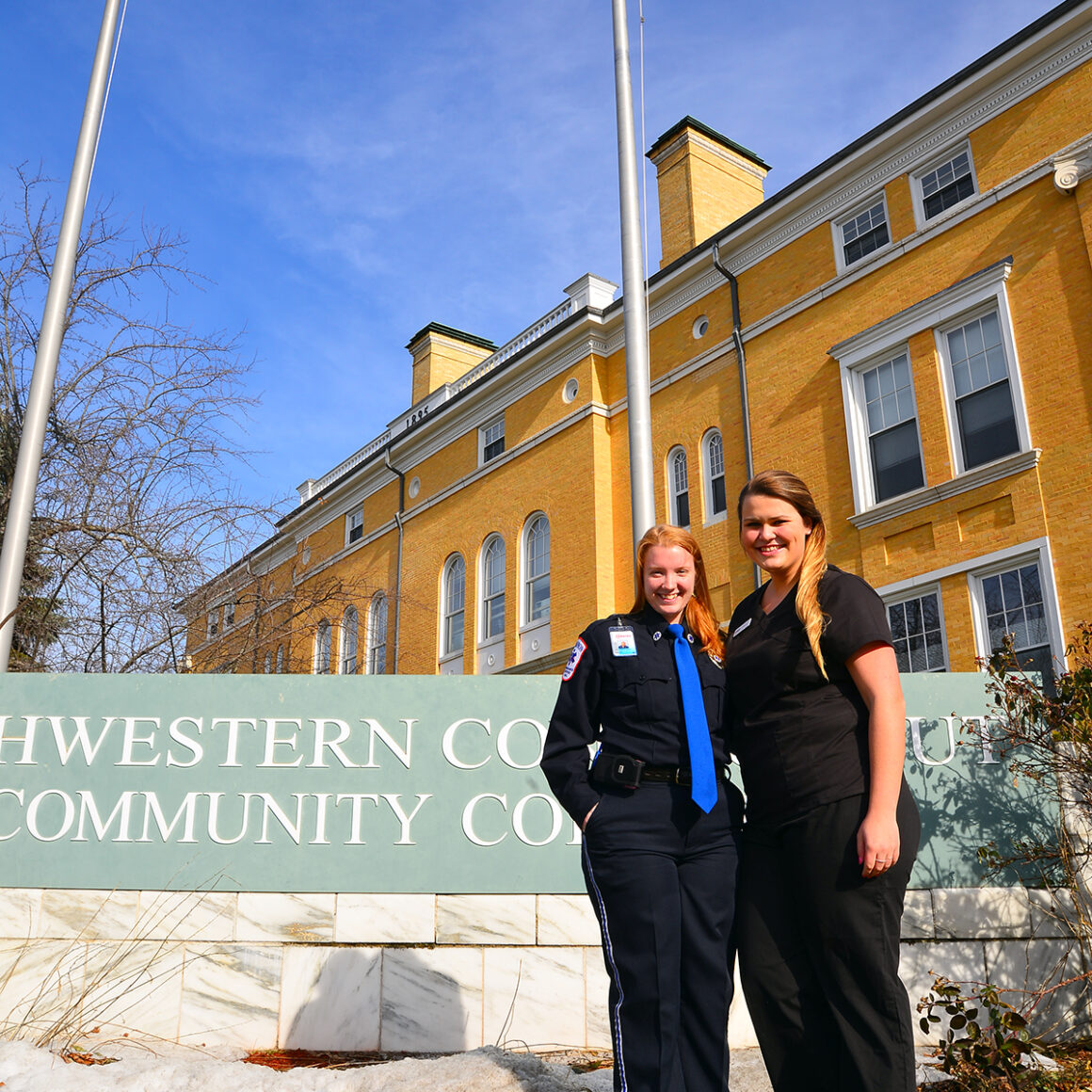 EMT and CNA students standing in front of Northwestern's college sign.